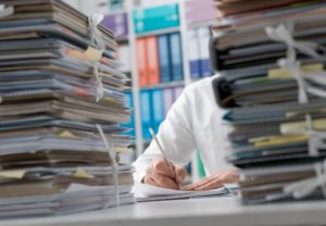 Man covered by stack of paperwork.