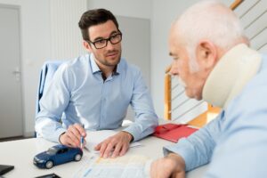 Insurance agent talking to the injured old man from car accident.