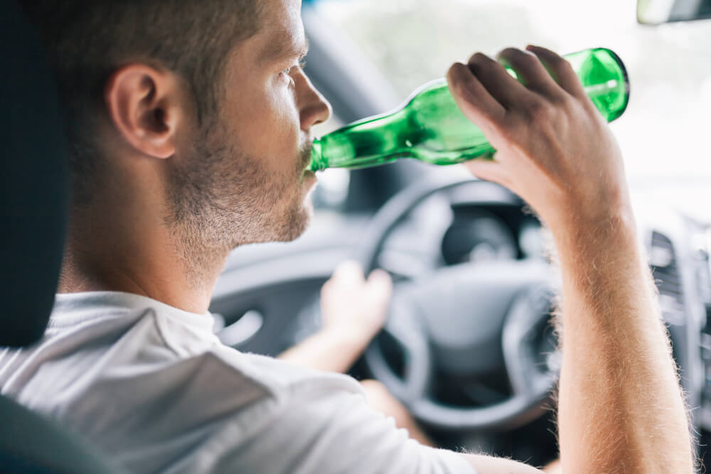 Driver drinking beer while driving in the highway.