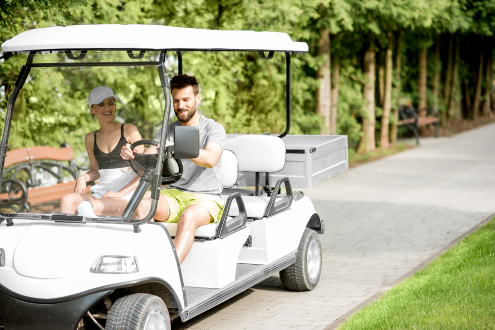 Happy couple golf carting inside the village.