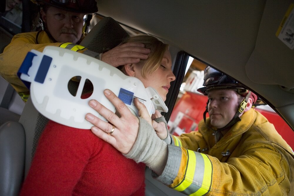 Firefighter rescuing injured victim from car accident.