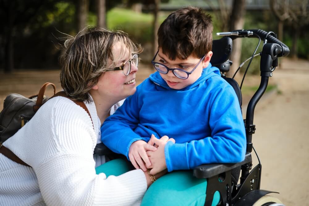 Woman comforting the kid in wheelchair.