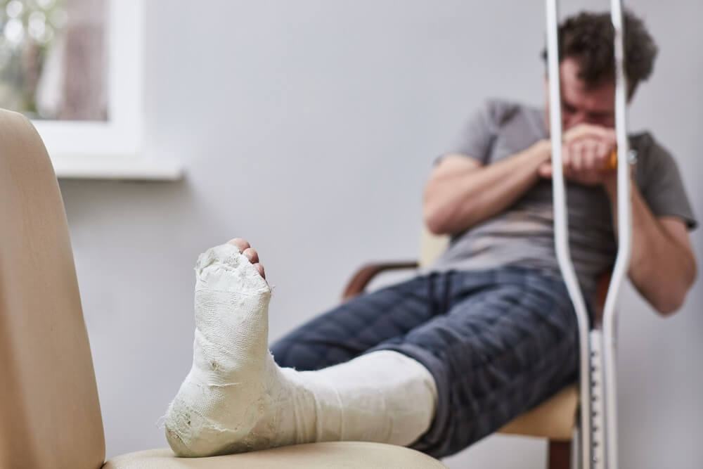 Injured man on crutches feeling sad.